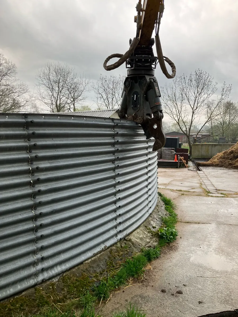 Kettenbagger mit Abbruchschere beim Zerlegen des alten Blechbehälters