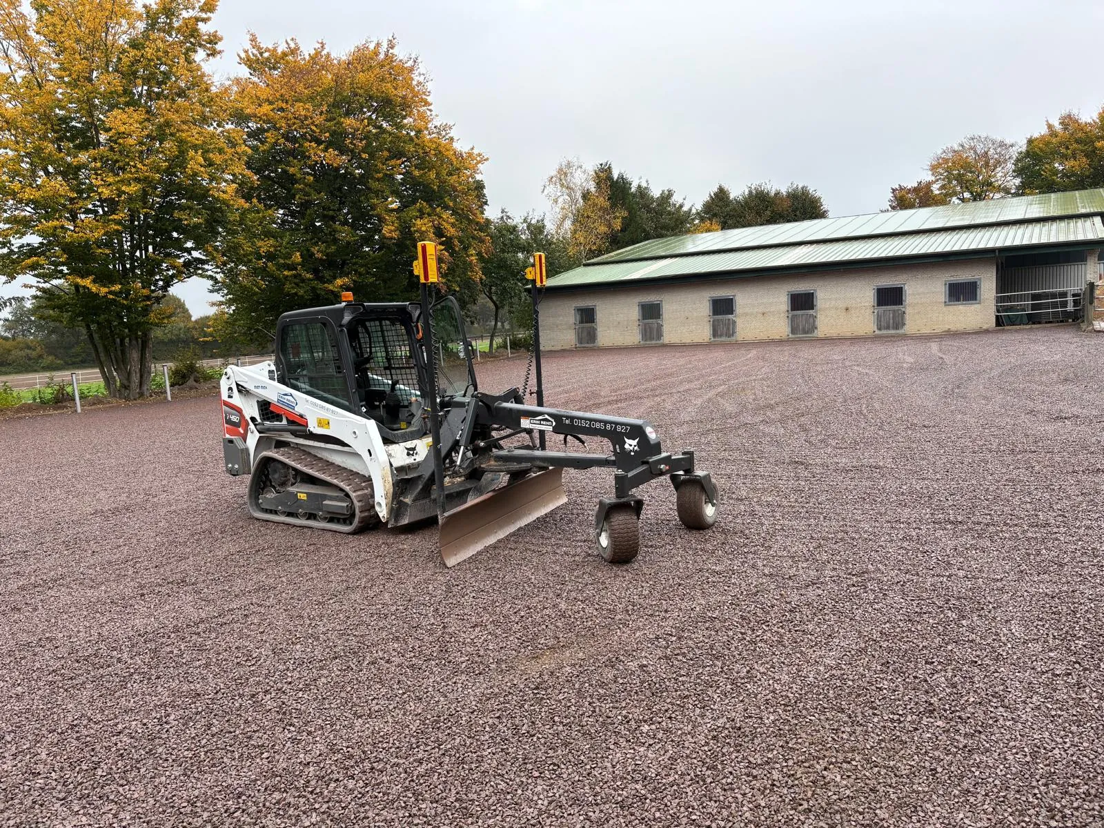 Bobcat T450 mit lasergesteuertem Planierschild auf fertig planierter Reitplatzfläche vor dem Stall
