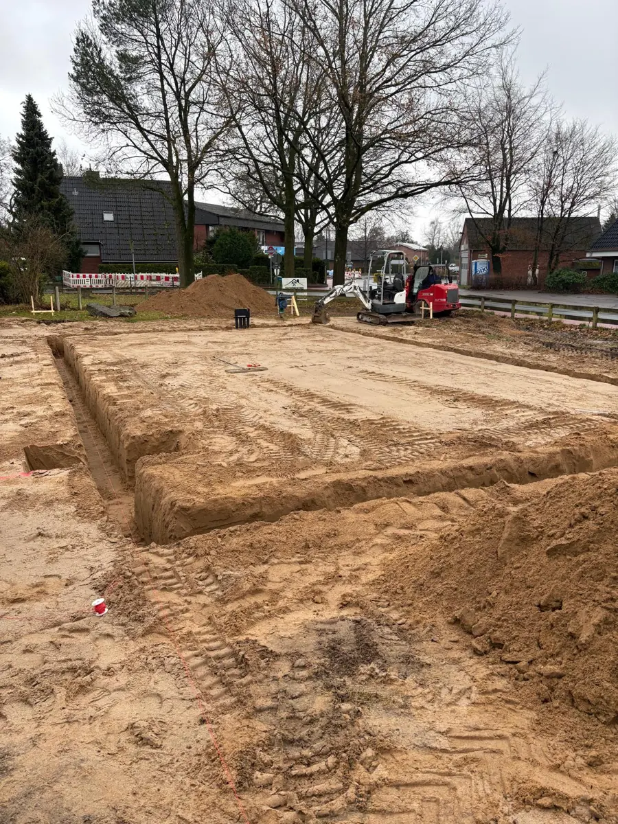 Minibagger auf der Baustelle eines Hausneubaus, Planum mit ausgehobenen Fundamentgräben