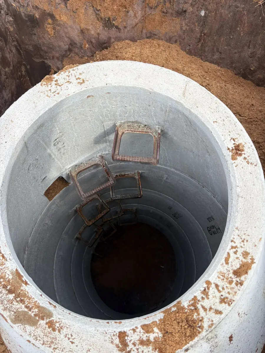 Blick von oben in den fertig gesetzten Sickerschacht aus mehreren Betonringen mit Steigbügeln